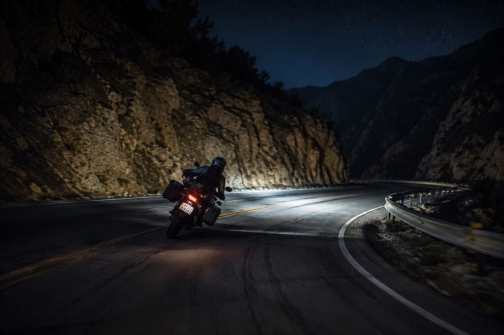 Motorcycle cornering at night with adaptive LED headlight illuminating the road through the curve