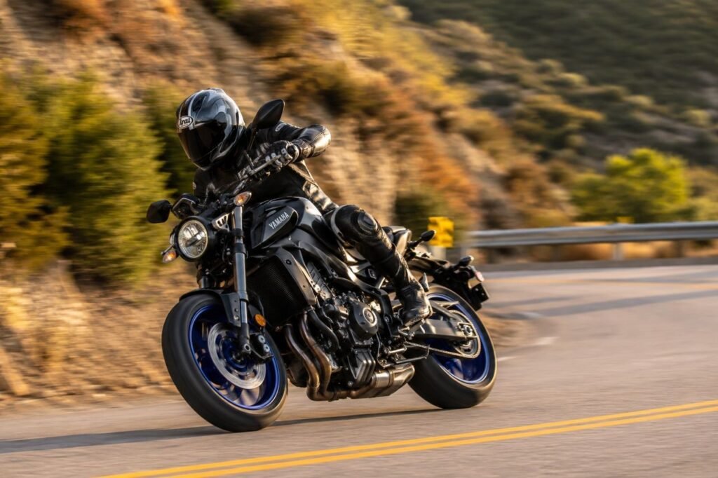 Sport motorcycle leaning into canyon corner showing front fork compression under braking