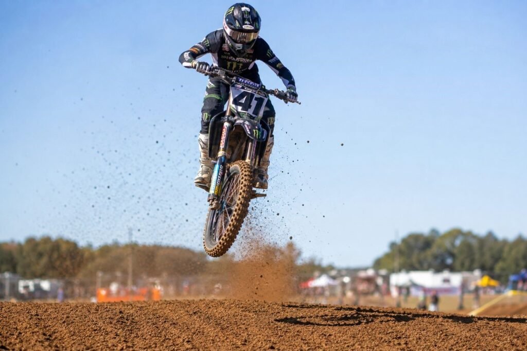 Motocross rider mid-air over jump showing front fork extension and rebound on dirt track