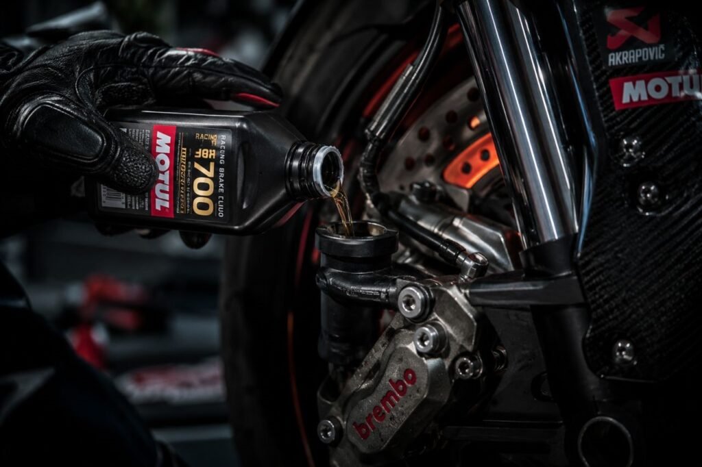 Best motorcycle brake fluid for high performance — rider pouring racing brake fluid into a sportbike caliper reservoir