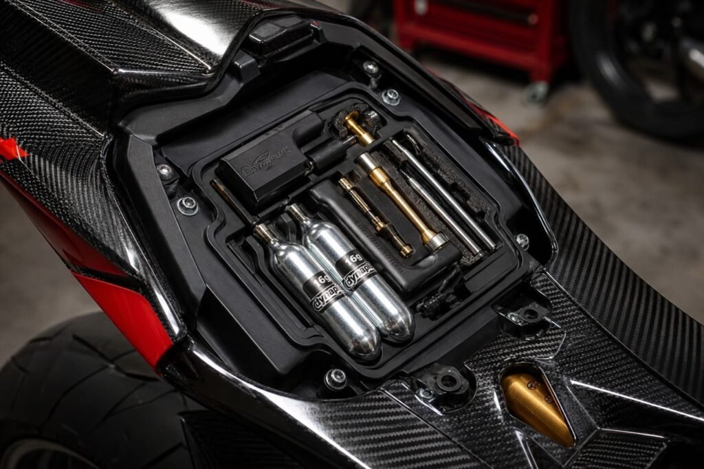 Compact motorcycle tire repair kit stored under a sportbike seat