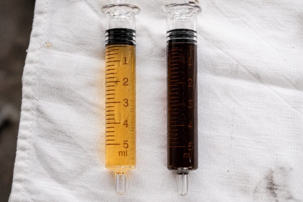 Fresh pale amber motorcycle brake fluid compared to dark brown degraded brake fluid