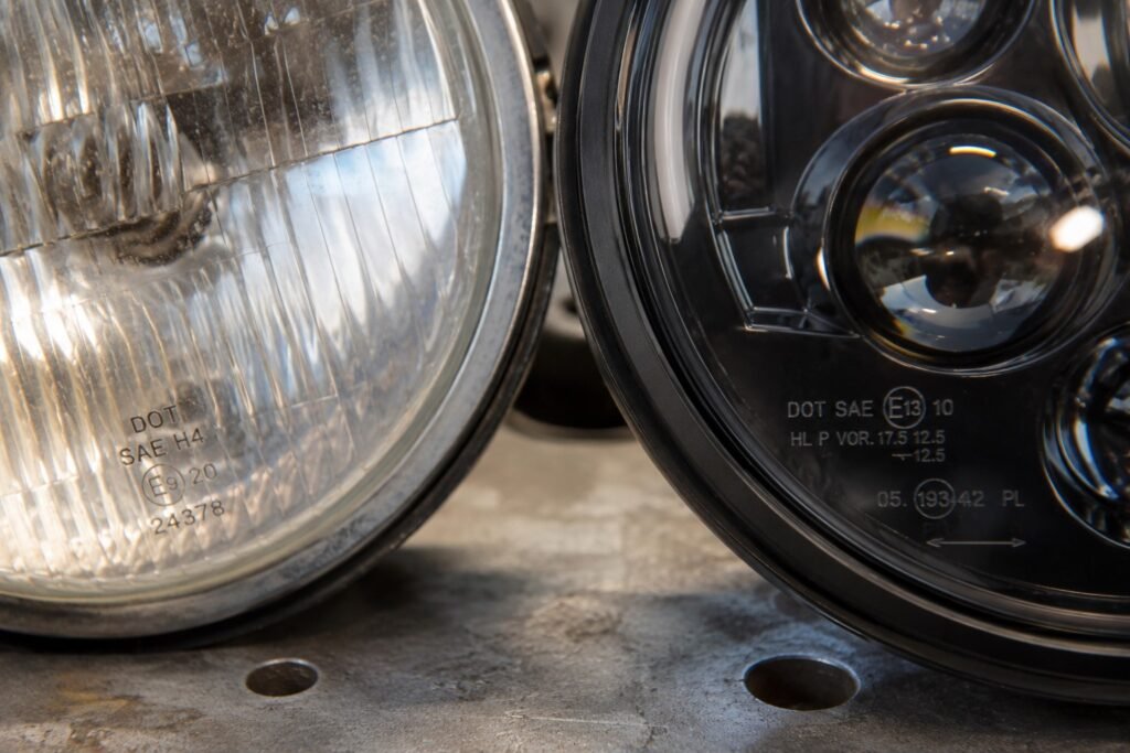 Side by side comparison of halogen and DOT-approved LED motorcycle headlight assemblies showing compliance stamps