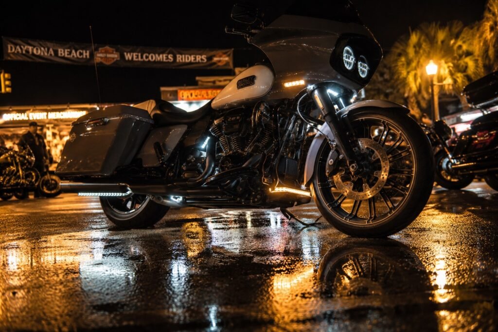 Custom Harley-Davidson with legal white and amber accent lights parked on wet street at night