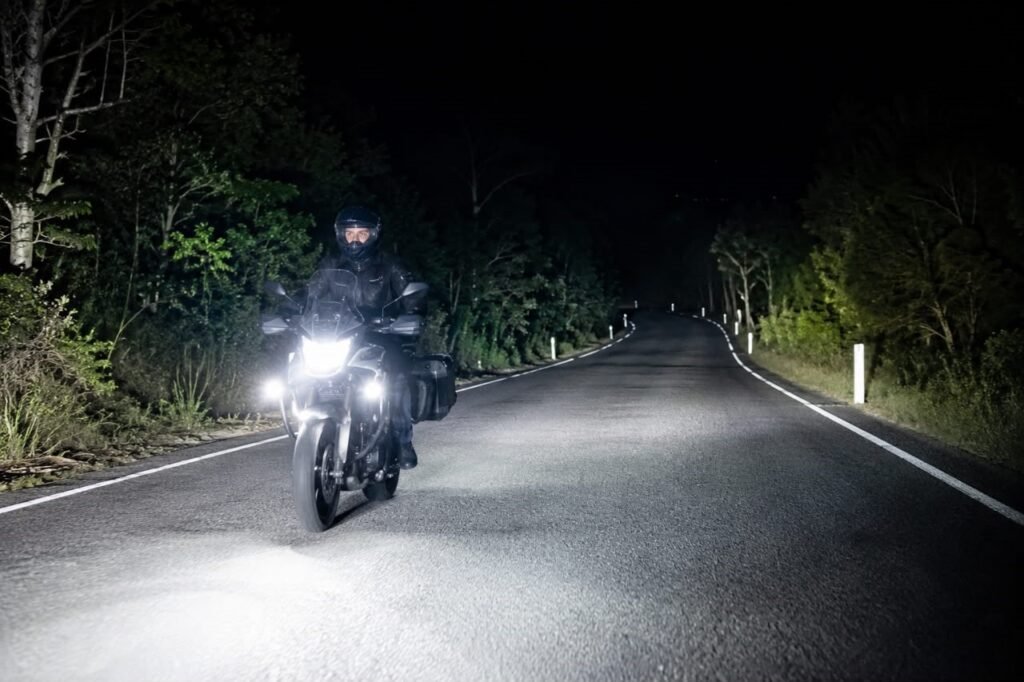 Motorcycle with upgraded LED headlight throwing a bright wide beam on a dark road at night