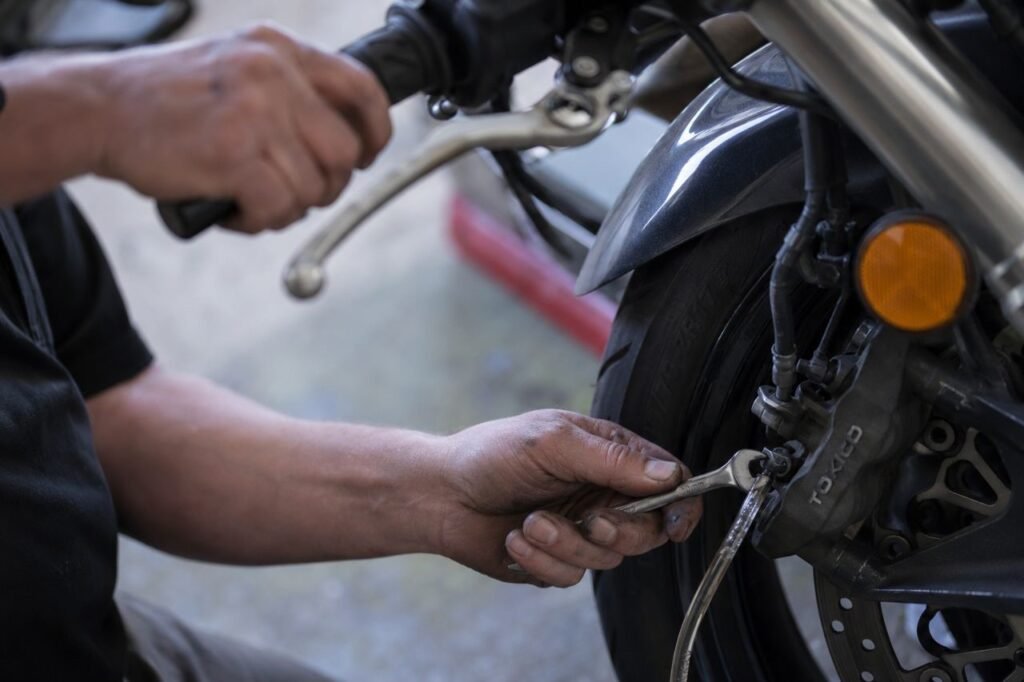 Hand squeezing motorcycle brake lever while bleeding front brakes