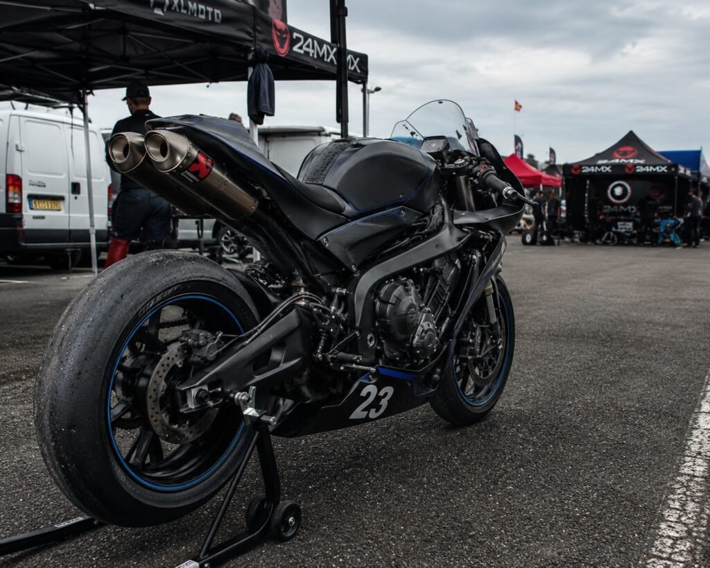 High-performance sportbike parked on a paddock stand at a race track showing the engine and exhaust setup.