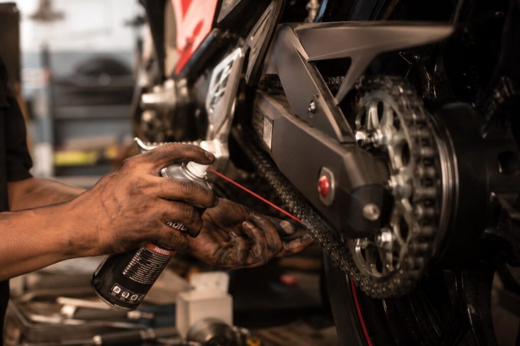 Mechanic lubricating a motorcycle chain in a workshop