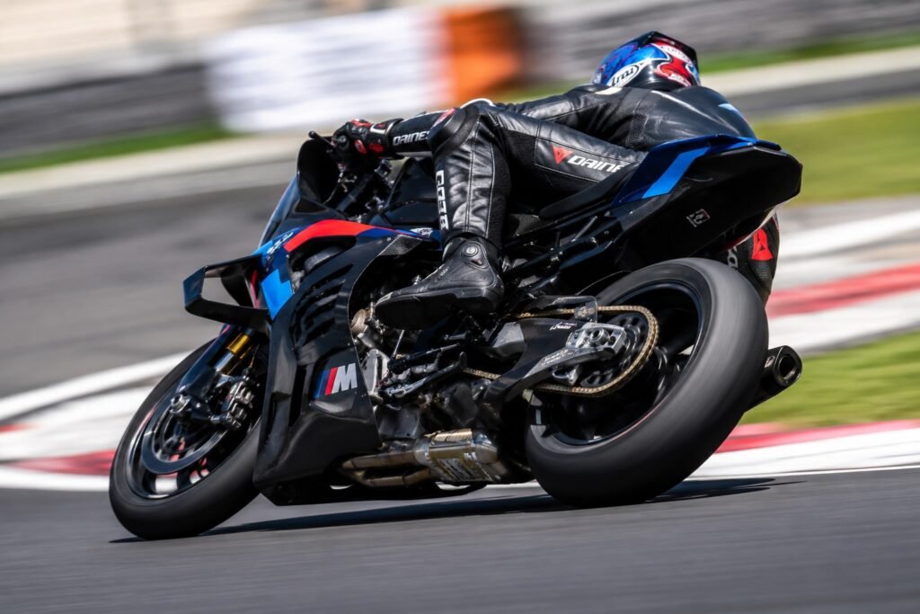 Sport motorcycle cornering on tarmac showing chain and sprocket drivetrain