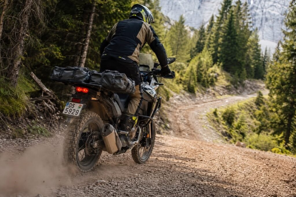 Adventure motorcycle rider on dirt trail with soft roll-top luggage