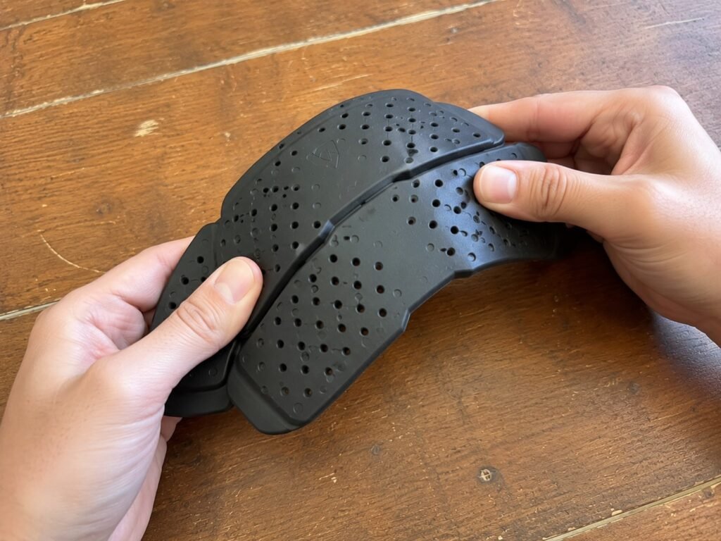 Hands flexing a D3O non-Newtonian motorcycle armor insert to show its soft, pliable state