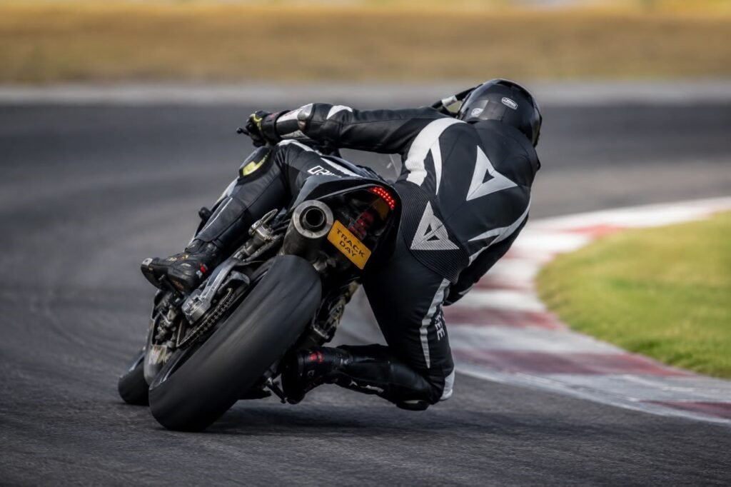 Rider using a motorcycle quickshifter to upshift mid-corner on a trackday sportbike