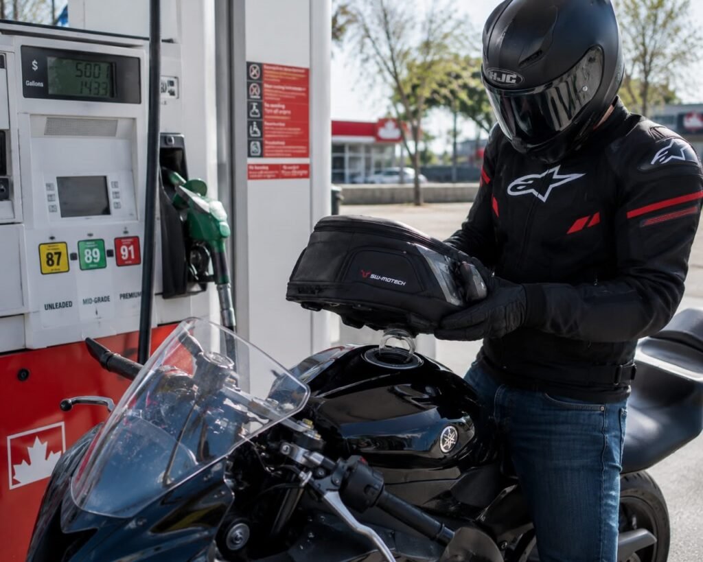 Rider removing a tank bag at a gas station to access the fuel cap